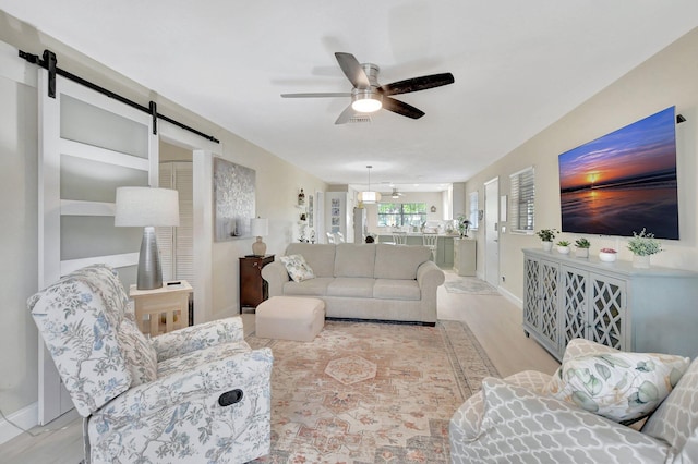 living room featuring a barn door, light hardwood / wood-style floors, and ceiling fan