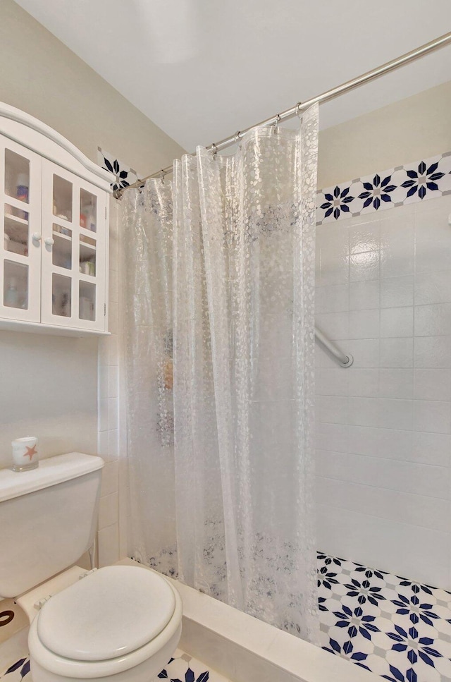 bathroom with curtained shower, tile patterned flooring, and toilet