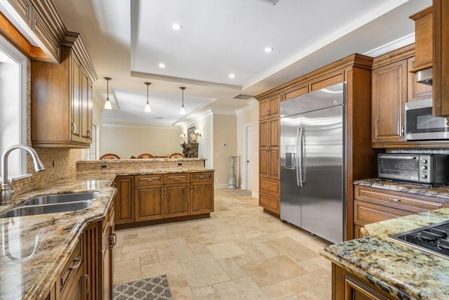 kitchen with sink, decorative light fixtures, appliances with stainless steel finishes, kitchen peninsula, and backsplash