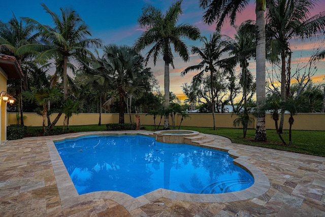 pool at dusk featuring a patio area and an in ground hot tub