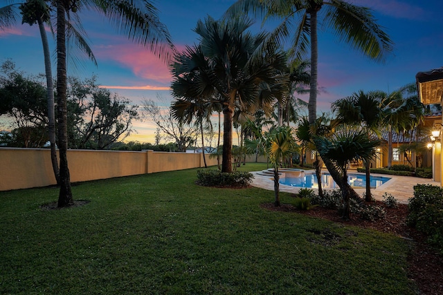 yard at dusk featuring a fenced in pool