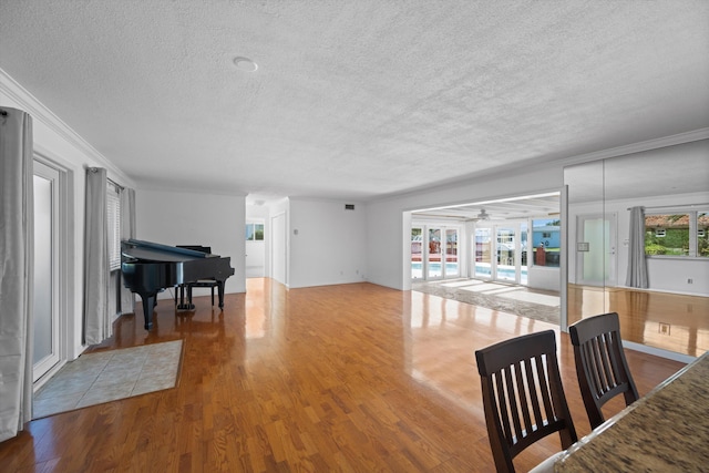 living room with hardwood / wood-style floors, ceiling fan, crown molding, and a textured ceiling