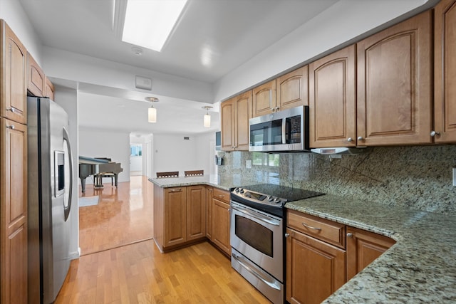 kitchen with light stone countertops, decorative backsplash, stainless steel appliances, and kitchen peninsula