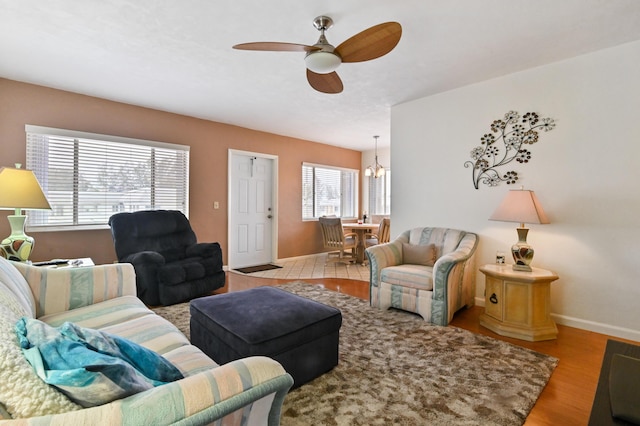 living room with ceiling fan with notable chandelier and light wood-type flooring