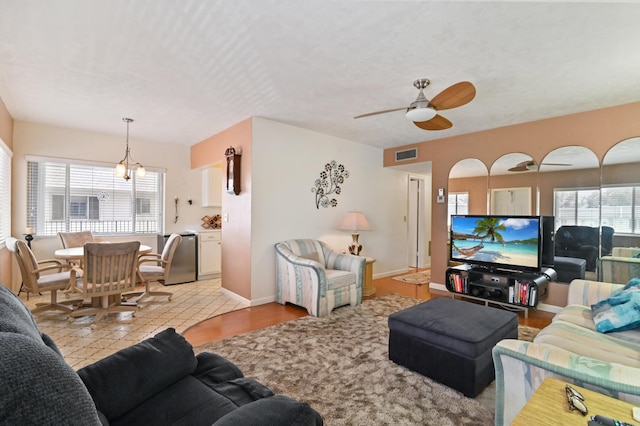 living room with ceiling fan with notable chandelier, light tile patterned flooring, and a wealth of natural light