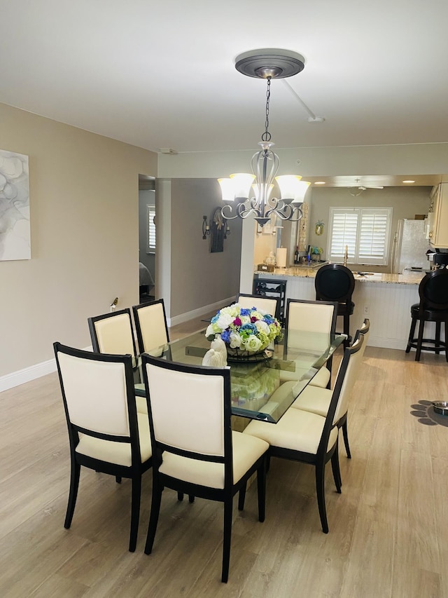 dining room with light hardwood / wood-style flooring and an inviting chandelier