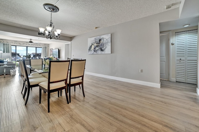 dining room with a textured ceiling, light hardwood / wood-style flooring, and an inviting chandelier