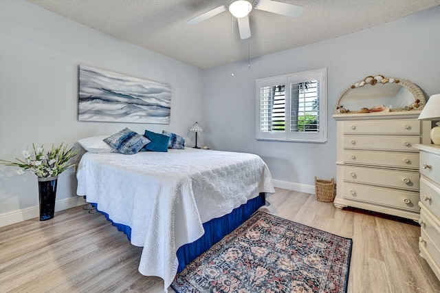 bedroom with ceiling fan, light hardwood / wood-style floors, and a textured ceiling