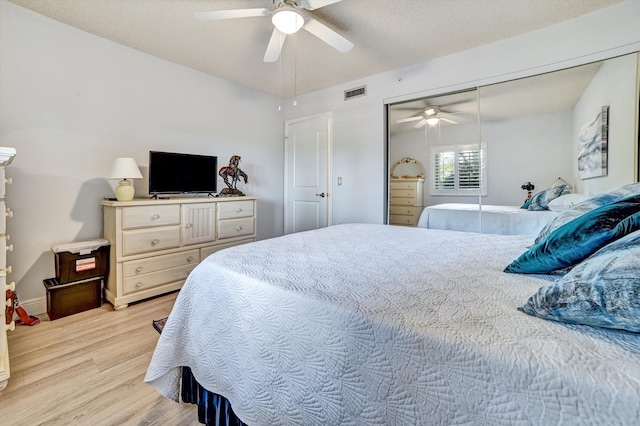 bedroom featuring a textured ceiling, light wood-type flooring, a closet, and ceiling fan