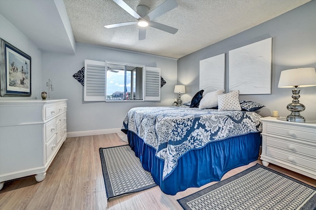 bedroom with ceiling fan, light hardwood / wood-style floors, and a textured ceiling