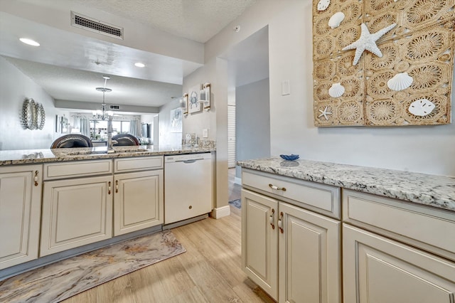 kitchen featuring cream cabinets, a textured ceiling, white dishwasher, and light hardwood / wood-style flooring