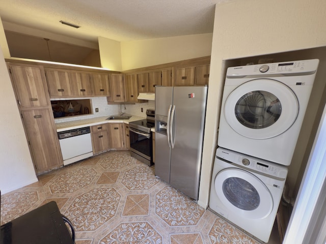 kitchen featuring sink, stainless steel appliances, backsplash, stacked washer / drying machine, and light tile patterned flooring