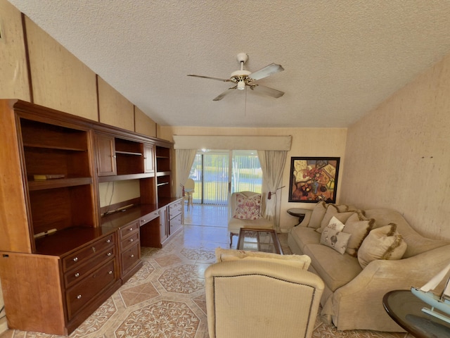 living room featuring ceiling fan, built in desk, a textured ceiling, and lofted ceiling