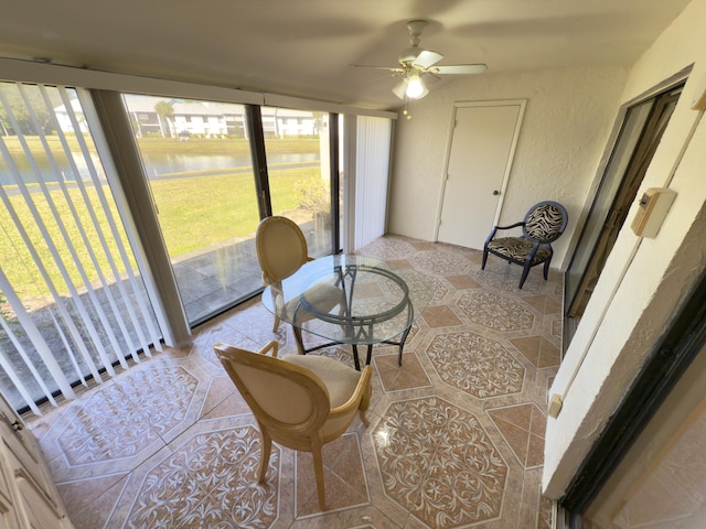 sunroom / solarium featuring ceiling fan, a healthy amount of sunlight, and a water view