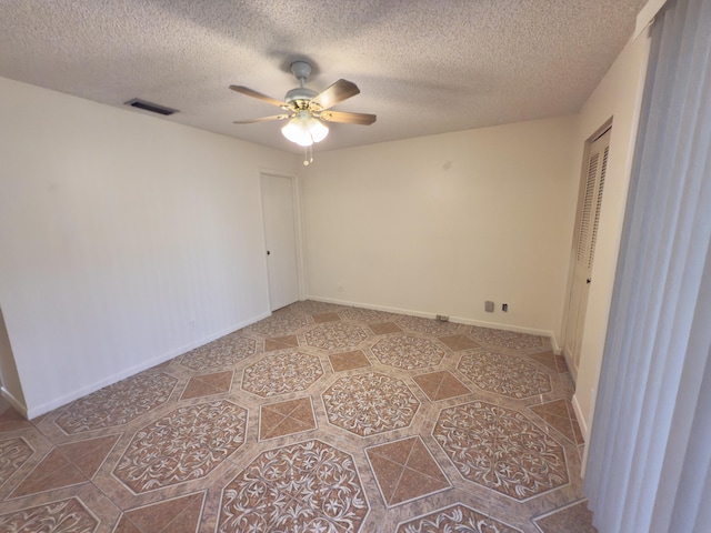 empty room with ceiling fan and a textured ceiling