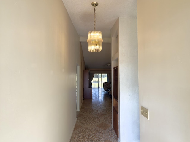 hall with a textured ceiling and an inviting chandelier