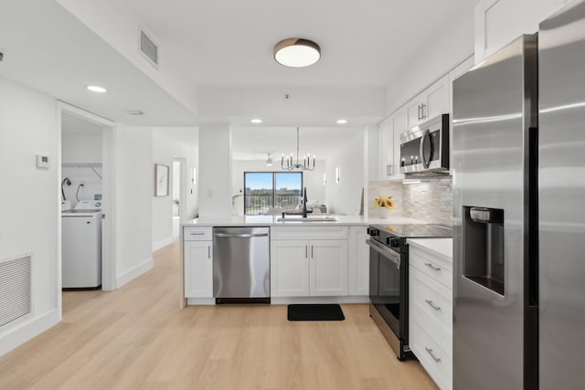 kitchen featuring washer / clothes dryer, a chandelier, decorative light fixtures, white cabinets, and appliances with stainless steel finishes