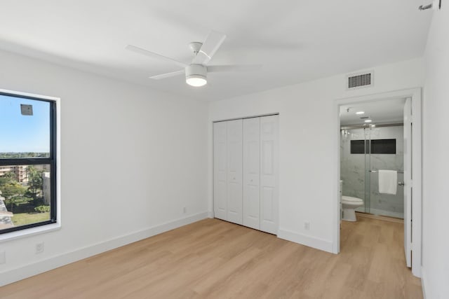 unfurnished bedroom with connected bathroom, ceiling fan, a closet, and light wood-type flooring