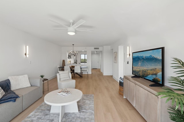 living room with ceiling fan with notable chandelier and light hardwood / wood-style floors