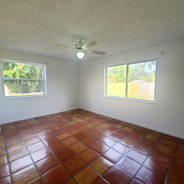 tiled empty room with a textured ceiling and ceiling fan