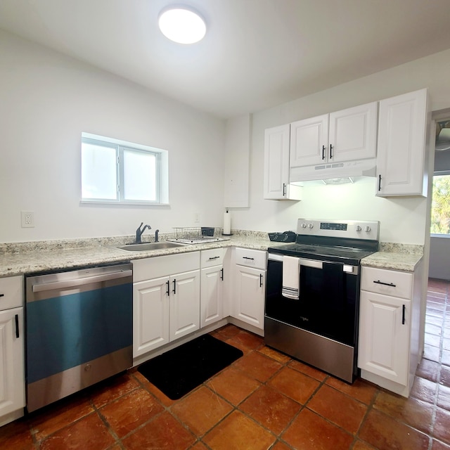 kitchen featuring appliances with stainless steel finishes, white cabinets, light stone countertops, and sink