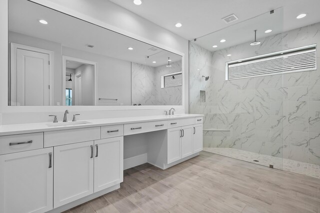 bathroom featuring hardwood / wood-style flooring, vanity, and tiled shower