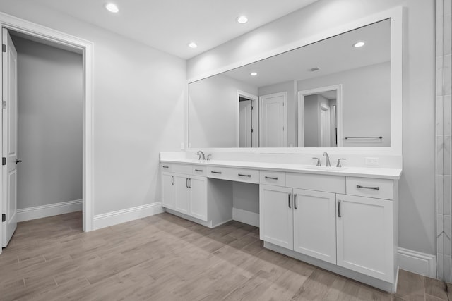 bathroom with double vanity, wood finished floors, and a sink