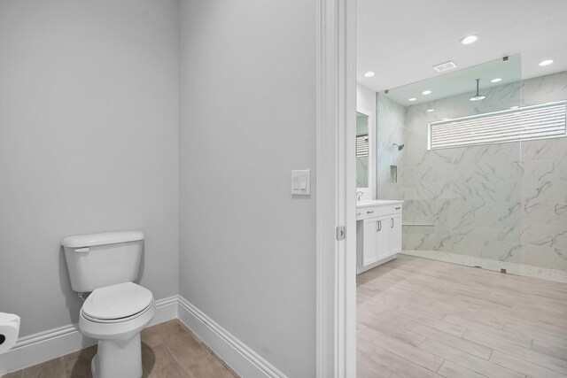 bathroom with a tile shower, vanity, and toilet