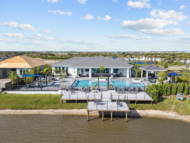 pool with a patio area, fence, and a water view