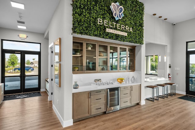 bar featuring light wood-style floors, plenty of natural light, wine cooler, and pendant lighting