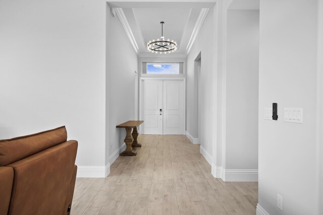 hall featuring light hardwood / wood-style floors, crown molding, and an inviting chandelier