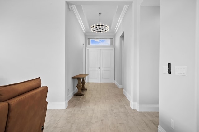 entryway featuring an inviting chandelier, baseboards, ornamental molding, and light wood-style floors