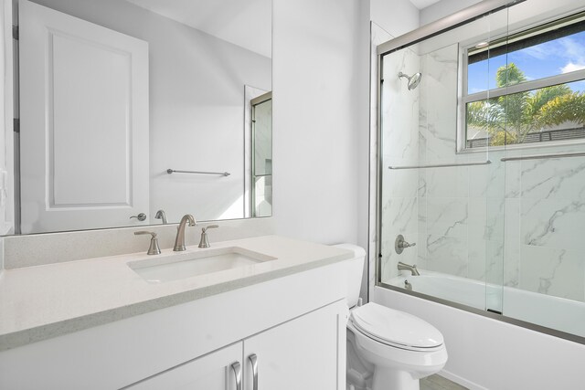 full bathroom featuring combined bath / shower with glass door, vanity, and toilet