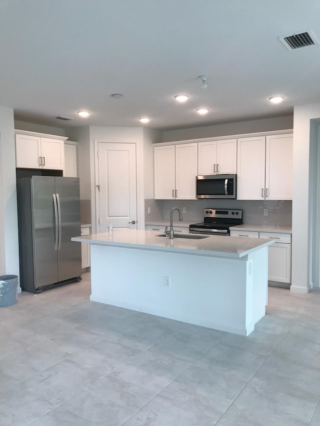 kitchen with a center island with sink, white cabinets, and appliances with stainless steel finishes