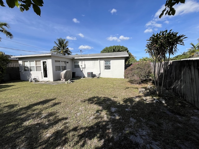 back of house with central AC unit and a lawn