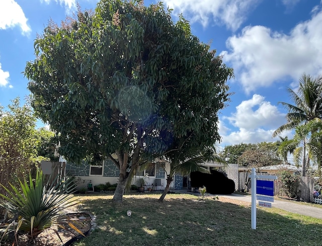 view of front of home with concrete driveway, a front lawn, and fence