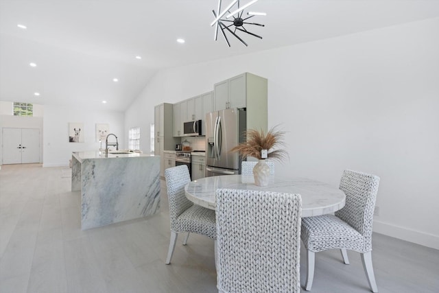 dining space featuring an inviting chandelier, plenty of natural light, lofted ceiling, and sink