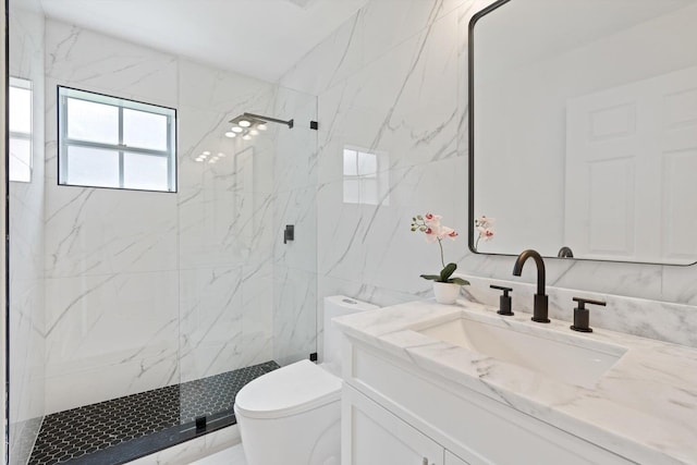 bathroom featuring vanity, toilet, tiled shower, and tile walls