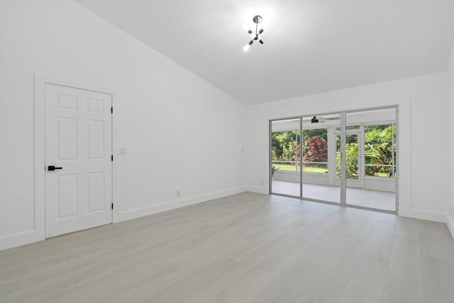 empty room featuring lofted ceiling, light wood-type flooring, and ceiling fan with notable chandelier