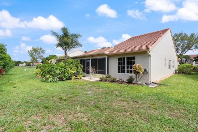 rear view of house featuring a sunroom and a lawn