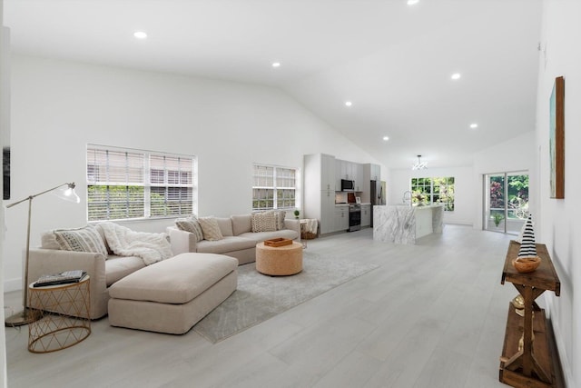 living room with sink, high vaulted ceiling, a healthy amount of sunlight, and light wood-type flooring