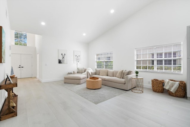 living room with a wealth of natural light, high vaulted ceiling, and light wood-type flooring