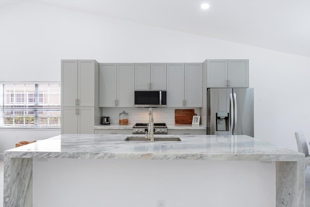 kitchen with stainless steel appliances, light stone counters, lofted ceiling, and sink