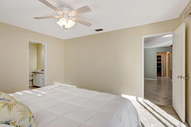 bedroom with ceiling fan, light colored carpet, and connected bathroom