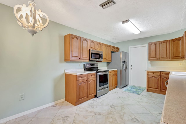 kitchen with pendant lighting, a notable chandelier, stainless steel appliances, and a textured ceiling