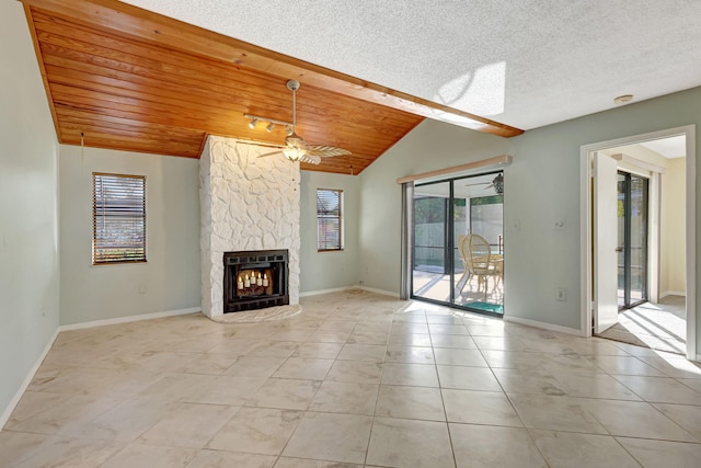 unfurnished living room with ceiling fan, a stone fireplace, vaulted ceiling, and wooden ceiling