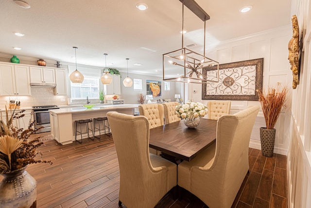 dining area with sink, a notable chandelier, and crown molding