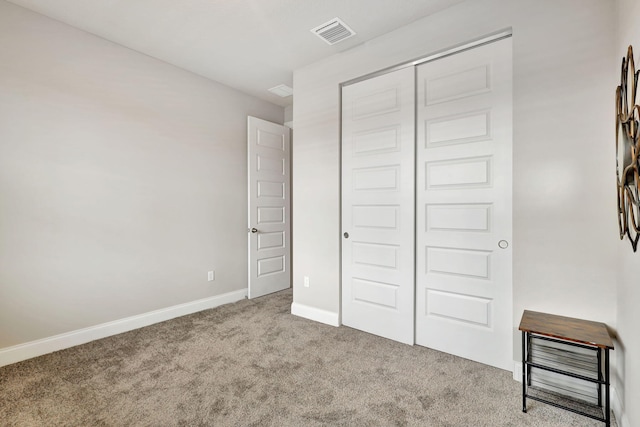 unfurnished bedroom with a closet and light colored carpet