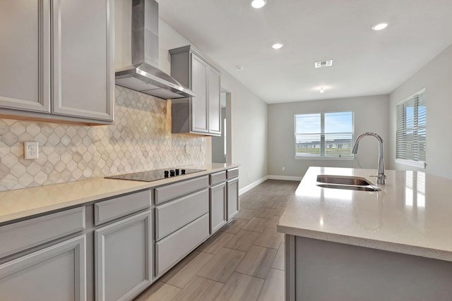 kitchen with gray cabinetry, sink, wall chimney exhaust hood, light stone countertops, and black electric cooktop