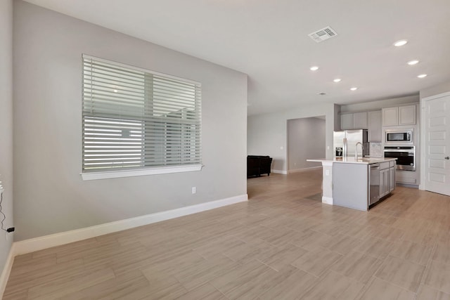 kitchen featuring a center island with sink, gray cabinetry, sink, and appliances with stainless steel finishes